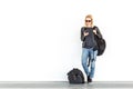 Fashionable young woman using her mobile phone while standing and waiting against plain white wall on the station whit Royalty Free Stock Photo