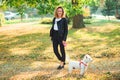 Fashionable young woman walking with her little west highland white terrier in a park. Best friends Royalty Free Stock Photo