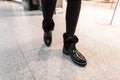 Fashionable young woman in warm leather winter boots with fur in vintage jeans walk on the store. Close-up of female legs in