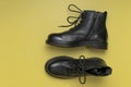 Fashionable youth black leather boots on yellow background flat lay top view. Stylish womens mens unisex boots. Grunge