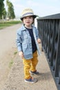 Fashionably dressed little boy in straw hat walks in summer