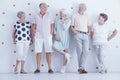 Fashionably dressed smiling senior people posing in bright studio