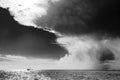 Weather changing in the Tropes, upcoming dramatic thunderstorm sky over calm sea with small fishing boat. Black and white photo Royalty Free Stock Photo