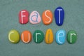 Fast Curier, creative sign composed with multi colored stone letters over green sand