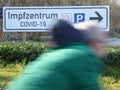 Fast cyclist drives past a German road sign . Impfzentrum Covid-19