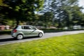 Fast driving small light green car taken with wide angle lens causing a strong motion blur effect