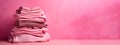 Fast fashion, Overconsumption, trends in fashion industry. Stack of pink clothing on pink background. Pile of trendy pink shirts, Royalty Free Stock Photo