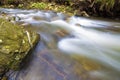 Fast flowing through wild green forest river with crystal clear smooth silky water falling from big wet stones in beautiful Royalty Free Stock Photo