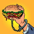 fast food addiction. The burger is handcuffed to the man hand. Street food and restaurants