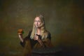 Fast food. Beautiful young girl with long blonde hair wearing medieval dress posing over dark vintage background. Retro Royalty Free Stock Photo