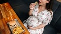 Fast food burger eat pregnant girl. Pretty young happy pregnancy woman eating tasty hamburger. Junk food concept. Royalty Free Stock Photo