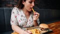 Fast food burger eat. Pretty Young Happy Woman Eating Tasty Hamburger. Junk Food Concept. Royalty Free Stock Photo