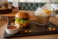 Fast food dinner consisting of hamburger, French fries and a Cup of sauce served on a wooden plate in restaurant Royalty Free Stock Photo