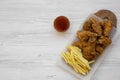 Fast food: fried chicken legs, spicy wings, French fries and chicken strips with sour-sweet sauce over white wooden background, Royalty Free Stock Photo