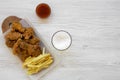 Fast food: fried chicken legs, spicy wings, French fries and chicken tenders with sour-sweet sauce and cold beer over white wooden Royalty Free Stock Photo