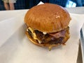 Fast Food Hamburger with Aioli Sauce, Cheddar Cheese, Mayonnaise and Bacon on White Burger Sheet / Street Food Cheeseburger Royalty Free Stock Photo