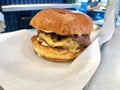 Fast Food Hamburger with Aioli Sauce, Cheddar Cheese, Mayonnaise and Bacon on White Burger Sheet / Street Food Cheeseburger Royalty Free Stock Photo