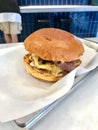 Fast Food Hamburger with Aioli Sauce, Cheddar Cheese, Mayonnaise and Bacon on White Burger Sheet / Street Food Cheeseburger Royalty Free Stock Photo