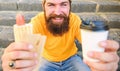 Fast food for lunch common idea. Hipster enjoy hot dog and drink paper cup beverage. Man bearded enjoy street food Royalty Free Stock Photo