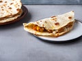 Fast food, quesadia with chicken and vegetables on a round light plate and baked tortillas in a plate