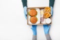 Fast food for two during coronavirus epidemic. Waiter hands in protective gloves gives box with burgers, french fries