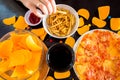 Fast food and unhealthy eating concept - close up of pizza,, french fries and potato chips and candies on wooden table top view