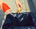 Fast food and unhealthy eating concept - hand throwing a burger with a plastic cup in garbage can on the city street Royalty Free Stock Photo