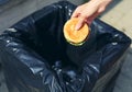 Fast food and unhealthy eating concept - hand throwing a burger in the trash Royalty Free Stock Photo