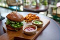 Fast food. Vegetarian burger with a chop, lettuce with sweet potatoes fries and two sauces. Tasty sandwich for lunch on wooden tab Royalty Free Stock Photo