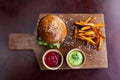 Fast food. Vegetarian burger with sweet potatoes fries and two sauces on wooden cutting board. Tasty sandwich for lunch in cafe. c Royalty Free Stock Photo