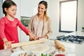 She is a fast learner. a middle aged mother and her daughter preparing a pizza to go into the oven in the kitchen at Royalty Free Stock Photo