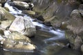 Fast mountain river is running between huge rocky stones