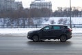 Fast moving black car on the winter city road. Compact city suv with man driving. Hyundai Tucson on the city street in motion