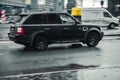 Fast moving black Range Rover Sport L320 on wet slippery road. Overspeed in city concept. SUV car on winter city road, side view