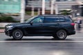 Fast moving BMW X7 car on the city road. Black premium SUV driving on motorway. Full-size auto in fast motion with blurred