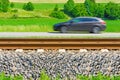 A fast moving car along the road goes alongside the railway tracks Royalty Free Stock Photo