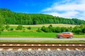 A fast moving car along the road goes alongside the railway tracks