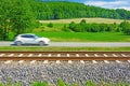 A fast moving car along the road goes alongside the railway tracks Royalty Free Stock Photo