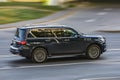 Fast moving Infiniti QX80 car on the city road. Gray SUV driving on motorway. Used auto in fast motion with blurred background