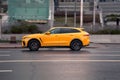 Fast moving orange Jaguar F-PACE on highway road. Overspeed in city concept. SUV car on city road in motion, side view