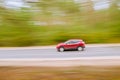 Fast moving red car on asphalt road. Panning shot