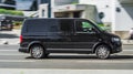 Fast moving Volkswagen Transporter T5 on the city road. Black minivan rides on street. Commercial auto in fast motion with blurred Royalty Free Stock Photo