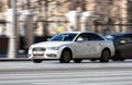 fast moving white car with motion blur effect. overspeed concept. Modern Audi A4 B8 auto goes fast on city road