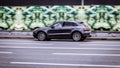 Fast moving white Porsche Macan SUV rides on a city road. A car on street in motion. Overspeed in city concept