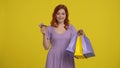 Fast payment and fast delivery. Redhaired woman with smartphone, credit card and shopping bags. Young woman in studio on