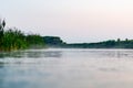 A fast river, with a haze of fog near the water and juicy green reeds near the shore. Royalty Free Stock Photo