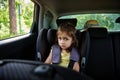 Fastened little girl to child safety seat inside car. Safe movement of children in the car Royalty Free Stock Photo