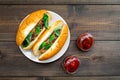 Fastfood concept. Make fresh hotdogs and home. bun for hot dogs with freid sausages and basil near tomato sause on dark Royalty Free Stock Photo