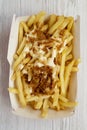 Fastfood: french fries with cheese sauce and fried onion in a paper box on a white wooden background, top view. Flat lay, from Royalty Free Stock Photo
