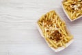 Fastfood: french fries with cheese sauce and fried onion in paper boxes on a white wooden background, top view. Space for text Royalty Free Stock Photo